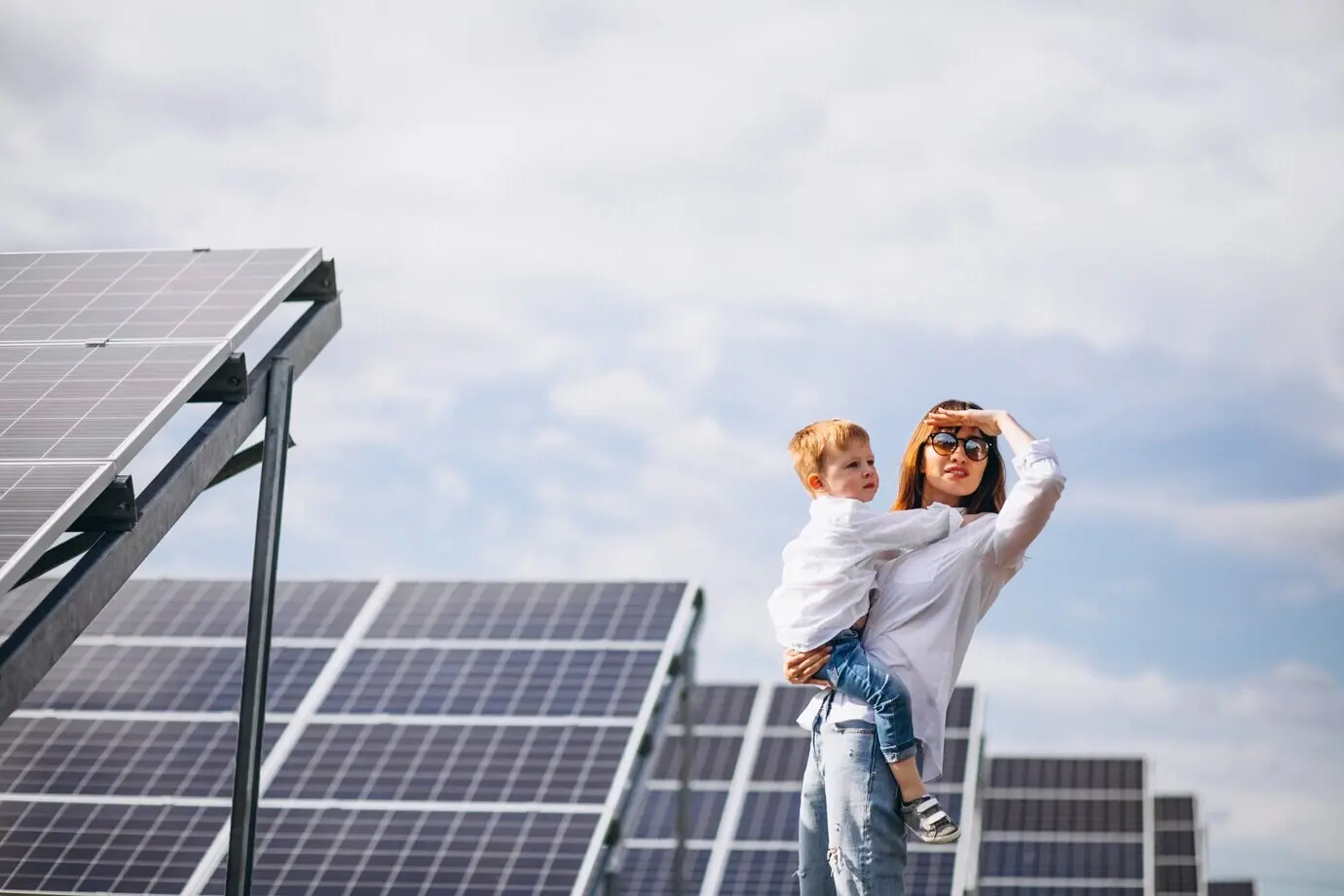 A mother with her young son beside solar panels.